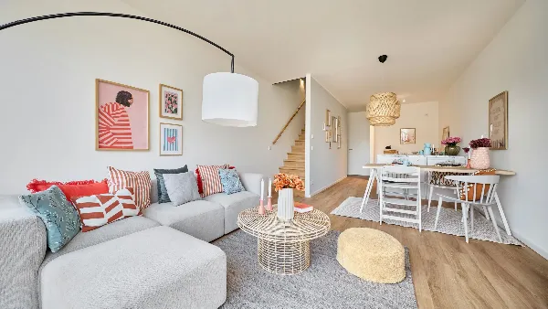 Rechts Esstisch und Küche des Musterhauses in UPTOWN Living, links die Treppe zur nächsten Etage und das Sofa des Wohnzimmers