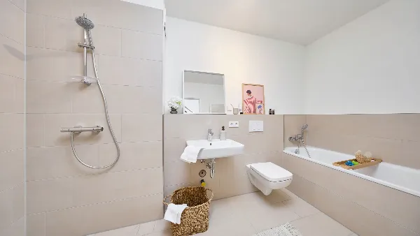 Badezimmer des Musterhauses in UPTOWN Living mit Dusche, Waschbecken, Toilette und Badewanne